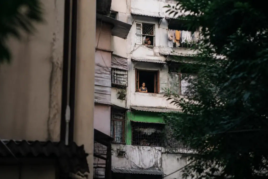 Immeubles collectifs serrés avec habitants visibles aux fenêtres
