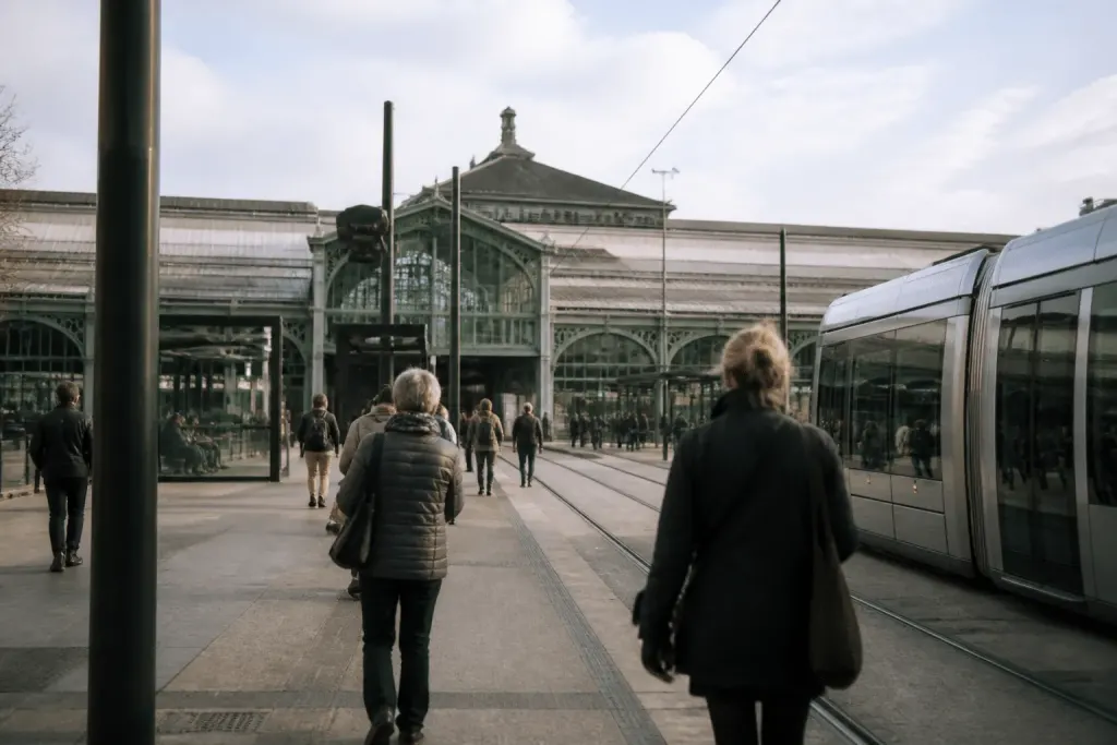 Gare ferroviaire avec tramway et passants en journée