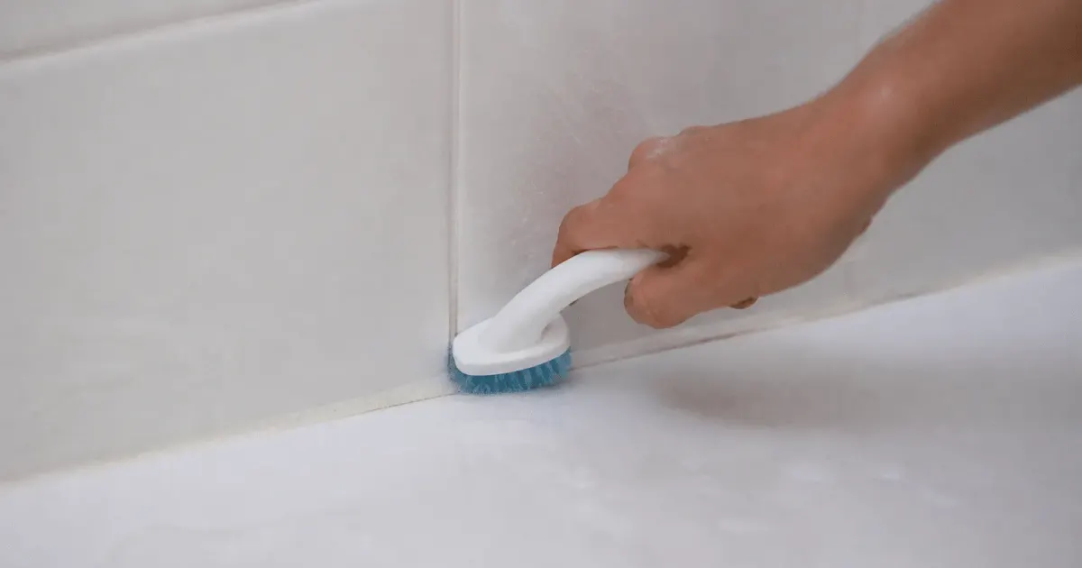 Brosse appliquee sur joints carrelage blanc salle bain