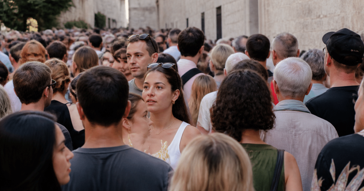 Foule dense de personnes debout dans rue urbaine avignonnaise