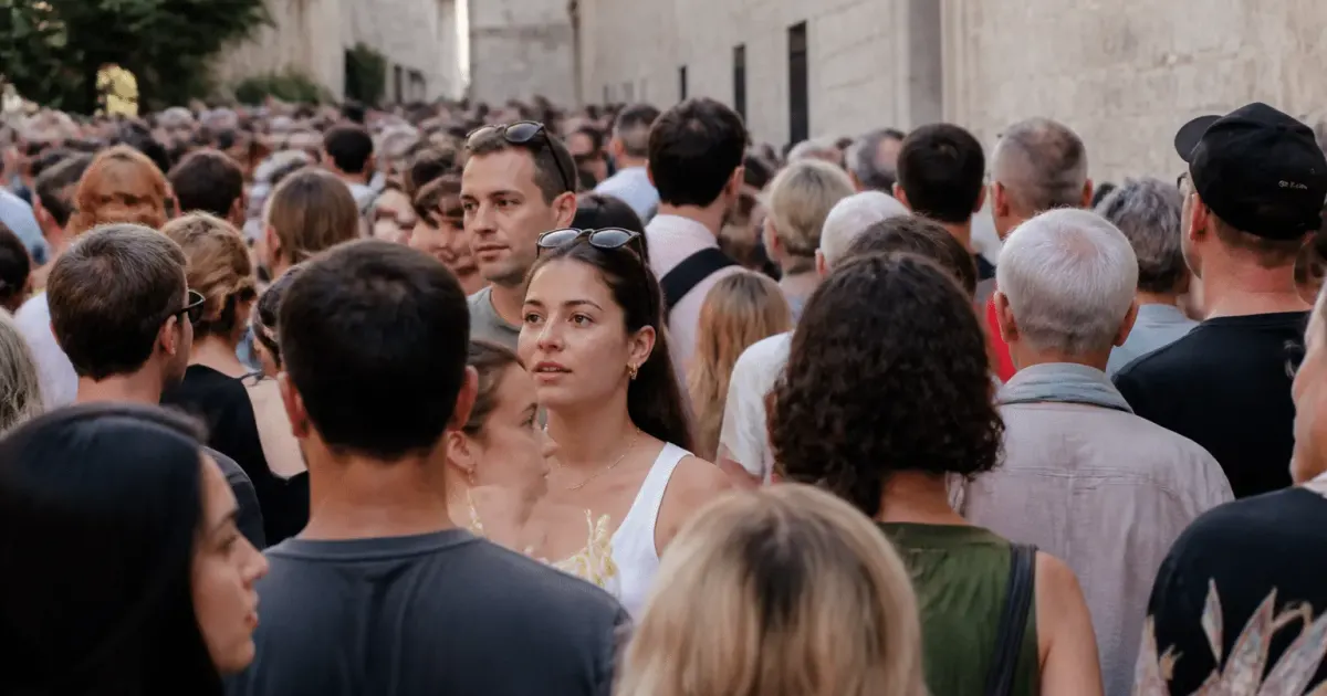 Foule dense de personnes debout dans rue urbaine avignonnaise