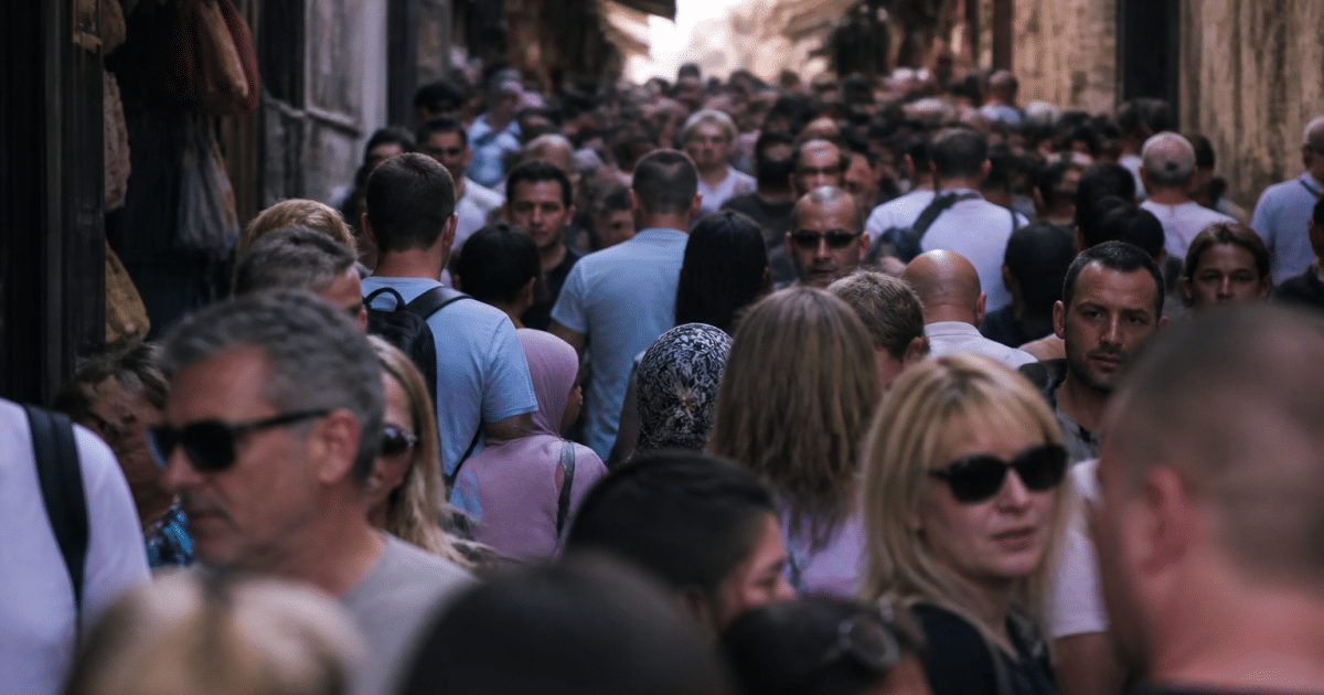 Foule dense de personnes debout dans rue urbaine étroite
