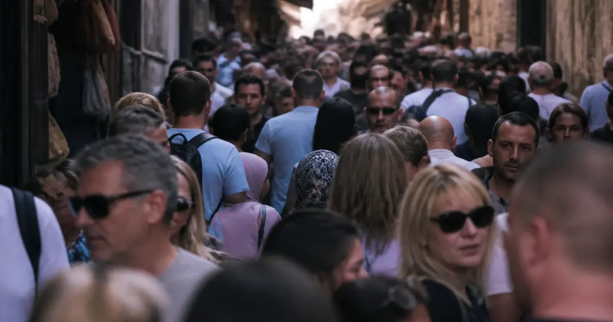 Foule dense de personnes debout dans rue urbaine étroite