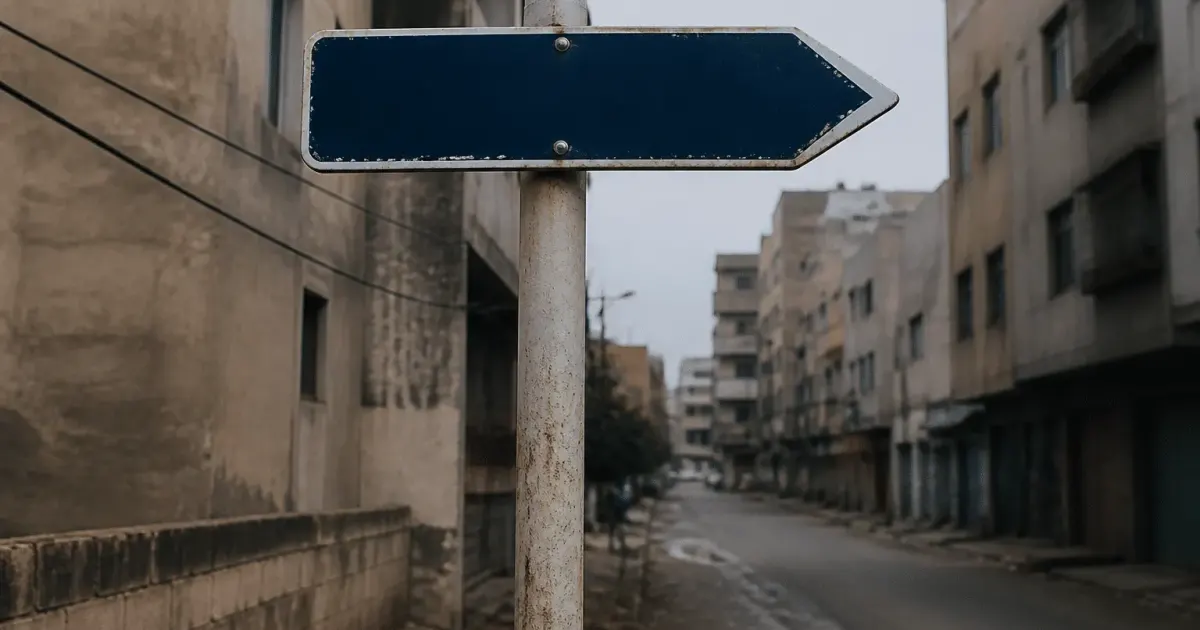 Panneau indicateur de rue pointant vers quartier urbain delabré