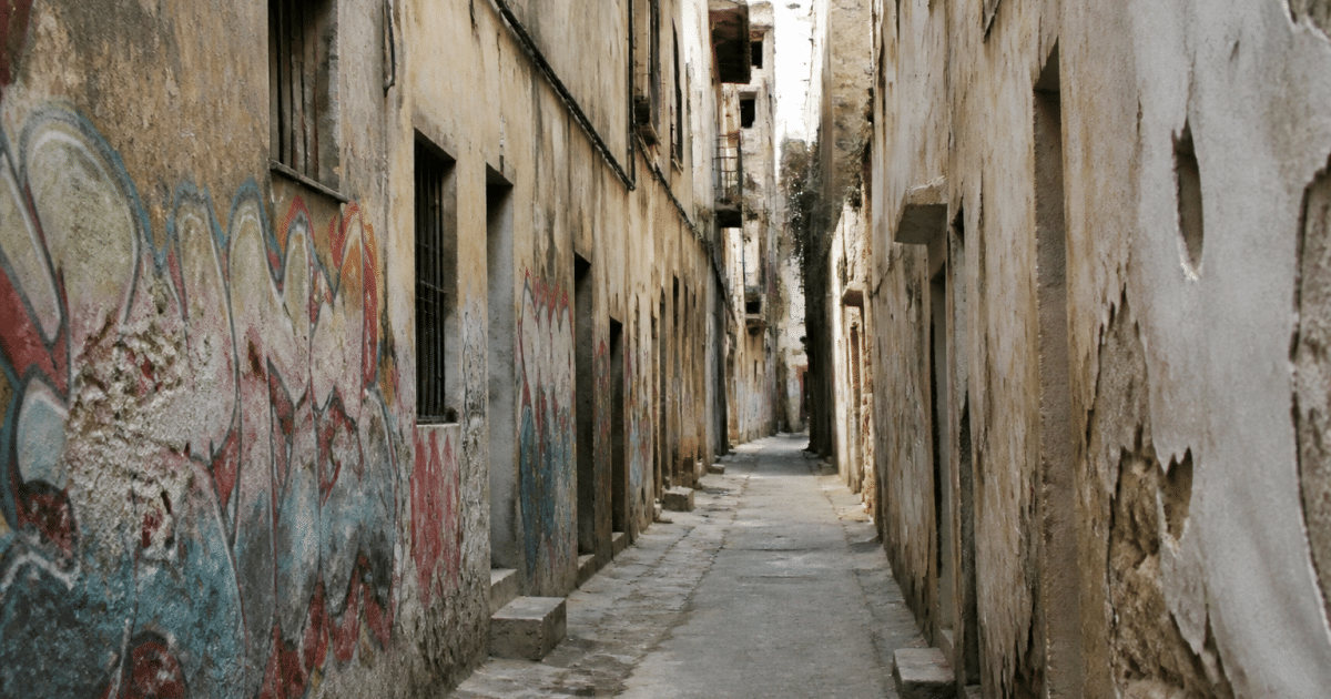 Rue urbaine étroite avec immeubles délabres et murs graffittes