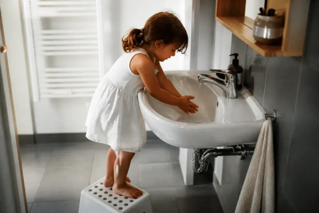 Enfant sur marchepied devant lavabo blanc abaissé