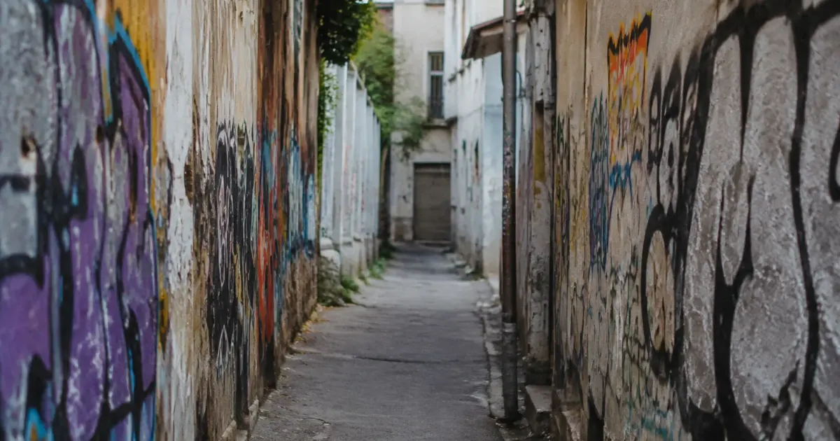 Ruelle urbaine encadree par murs degrades couverts de tags