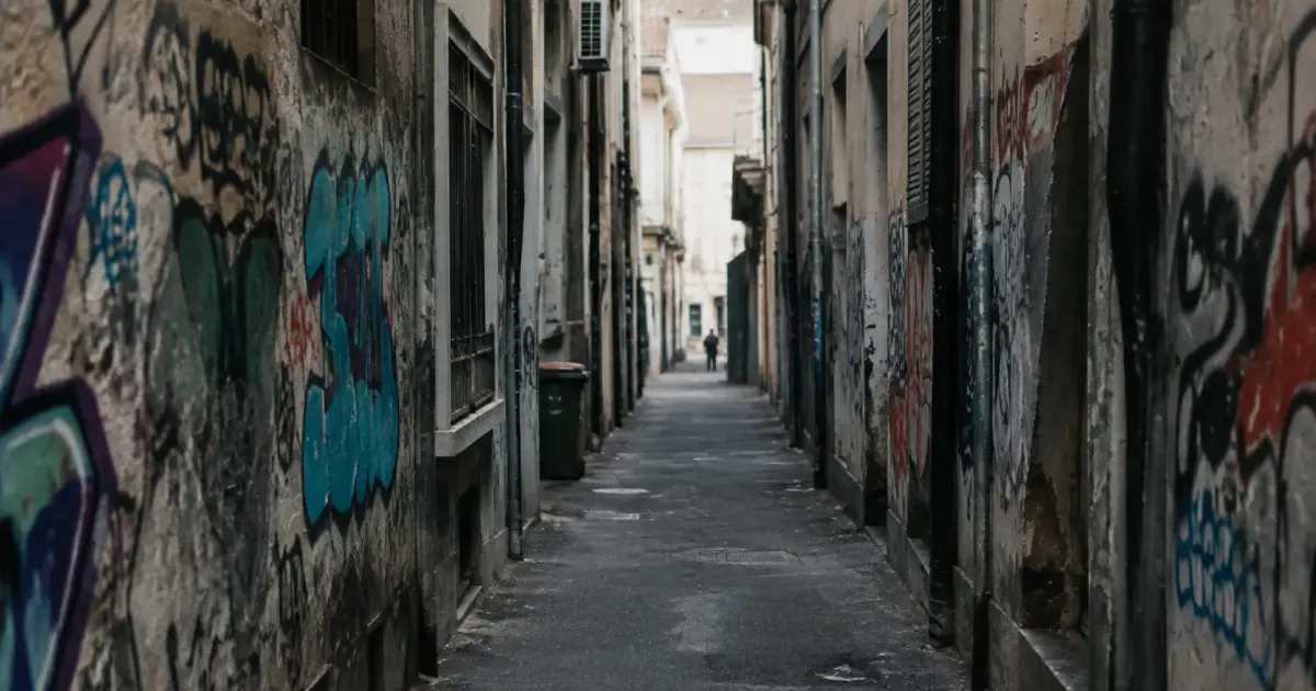 Rue urbaine sombre avec murs couverts graffitis et usure