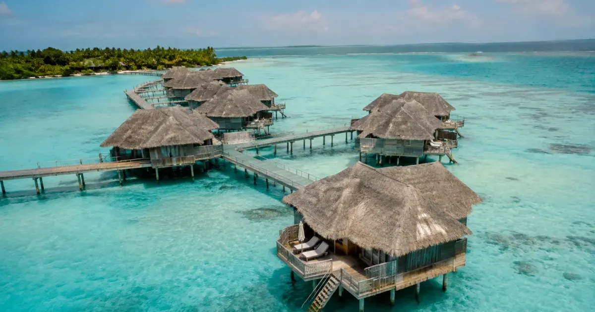 Vue aerienne maisons sur pilotis bordant un lagon turquoise